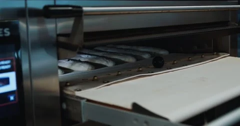 Baker loading raw bread inside a hot oven in the kitchen Stock Footage 220148571