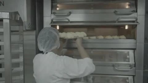 Baker loading trays of dough into a large industrial oven. Stock-Footage 327354932