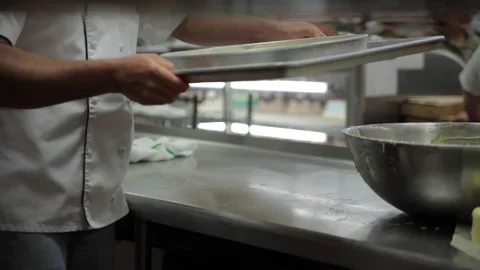 A baker loads a cake onto a baking rack Stock Footage 231414738