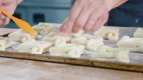 Baker lubricating the top surface of sweet baking before input into oven Stock Footage 91297510