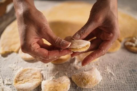 Baker makes dumplings with cottage cheese from raw dough with filling, close- Stock Photos