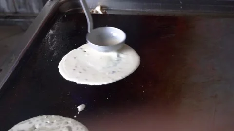 A baker makes pancakes on a large hot baking sheet Stock Footage 324450828