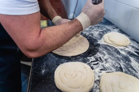 Baker makes pattern on blank for Uzbek flatbread Stock Photos