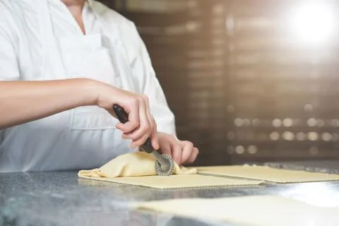 Baker makes some rolls from raw dough and filling, using special instrument Stock Photos