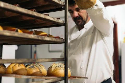 Baker making bread at a bakery. Stock Photos