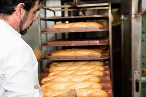 Baker making bread at a bakery. Stock Photos