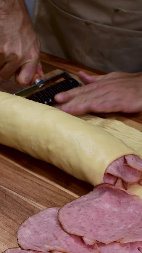 Baker making decorative dough lattice for traditional ham bread rolls Видео 335961618