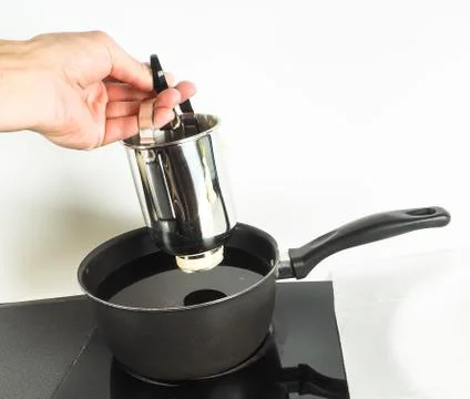 Baker making donuts with a squeeze container into hot oil in small kettle Stock Photos