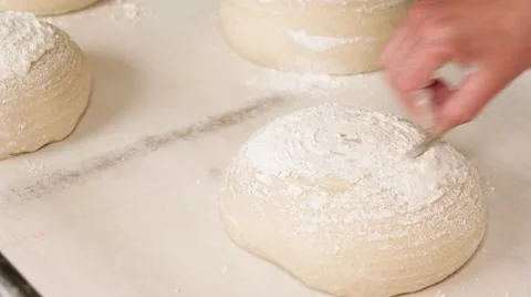 Baker making patterns on raw bread using a blade, closeup Stock Footage 64471050