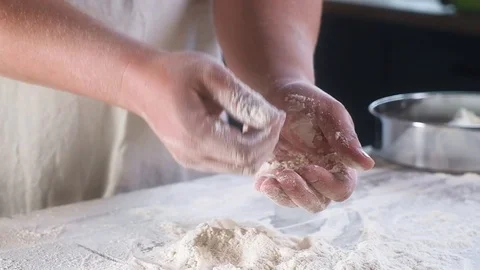Baker man claps his hands with flour several times. Cleans hands. Video stock 108820708