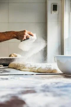Baker man hand spreading flour to dough. Stock Photos