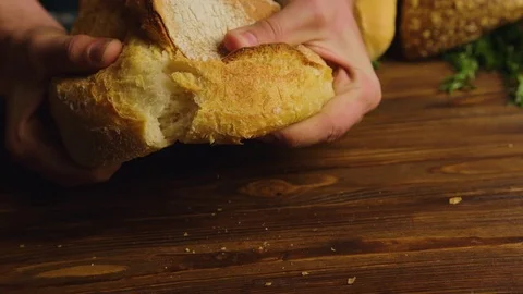 Baker man hands tearing fresh bread on a half. Male hands breaking whole grain Stock Footage 74753672