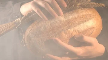 Baker man holding rustic organic loaf of bread and wheat in hands - rural bakery Stock-Footage 86018703