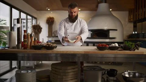 Baker man kneading dough in kitchen. Chef cooking pizza bread in restaurant. Stock Photos