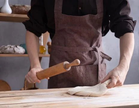 Baker man kneading or making dough with rolling pin and bakery ingredients fo Stock Photos