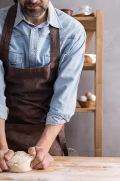 Baker man kneading or making dough or bread cooking. Bakery concept and woode Stock Photos