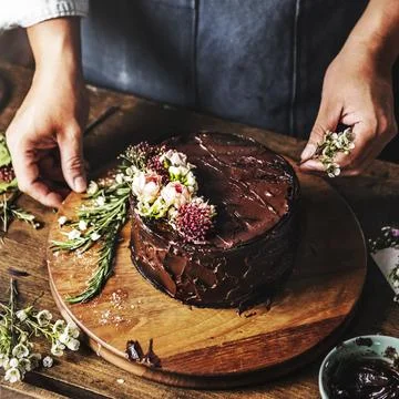 Baker Man Using Flowers Decorating Chocolate Cake Stock Photos