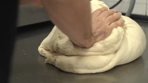 Baker manually kneading raw bread dough on a table (2) Stock Footage 251344772