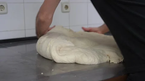 Baker manually kneading raw bread dough on a table 스톡 동영상 251368684
