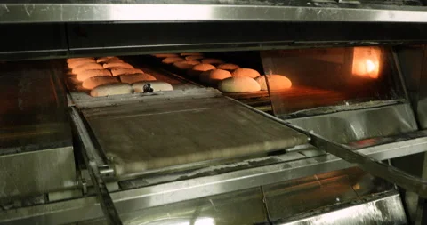 A Baker Manually Pulling The Deck Oven Loader, Moving The Raw Bread Dough Stock Footage 142112824