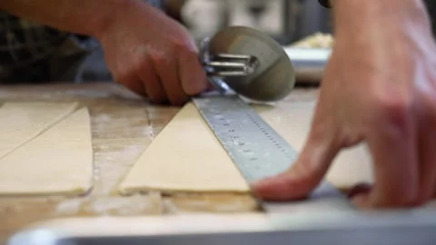 Baker maticulously measures and cuts triangle pieces of dough for Stock Footage 240912664