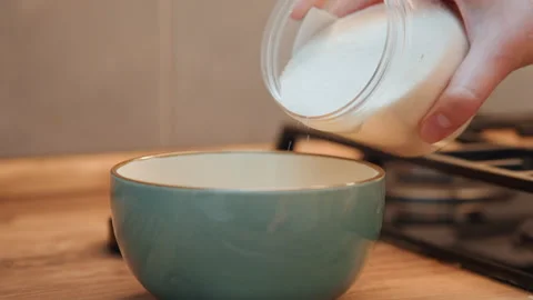 Baker measures ingredients. Sugar is poured into bowl carefully. Baker is 動画素材 345530056