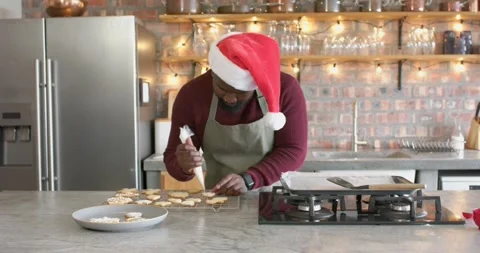 Baker is picking up piping bag, outlining star cookies on marble island for Stock Footage 341467377