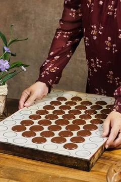 Baker Piping Chocolate Macaron Shells on Silicone Mat While Preparing French Coo Photos