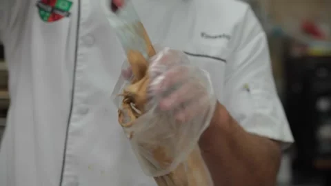 Baker places brown icing in a icing bag. Stock Footage 231414391