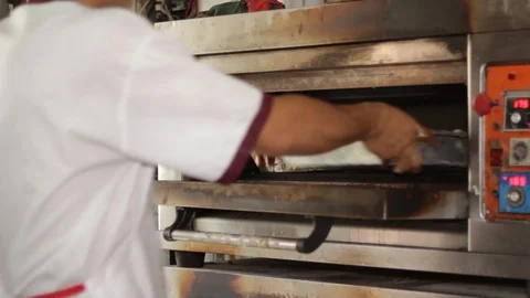 Baker placing cakes in oven Stock Footage 90771532