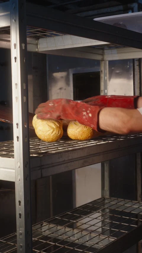 Baker Placing Freshly Baked Bread on a Bakery Rack Stock Footage 345491368