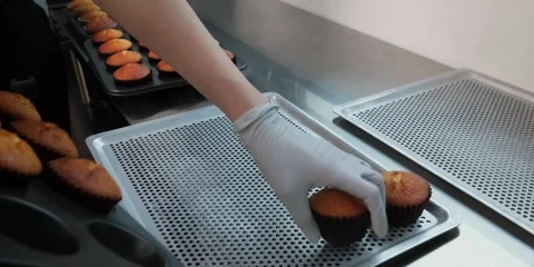Baker Placing Freshly Baked Muffins on Cooling Tray in Commercial Kitchen Stock Footage 343588608