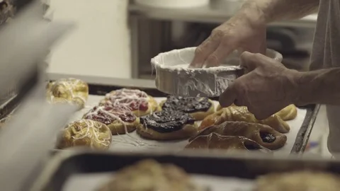 Baker placing frosting on batch of danishes Stock Footage 73900752