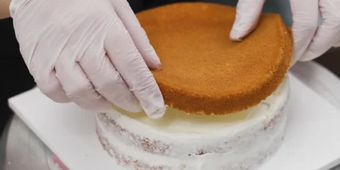 Baker Placing Top Sponge Layer on Crumb Coated Layer Cake Stock Footage 343588405