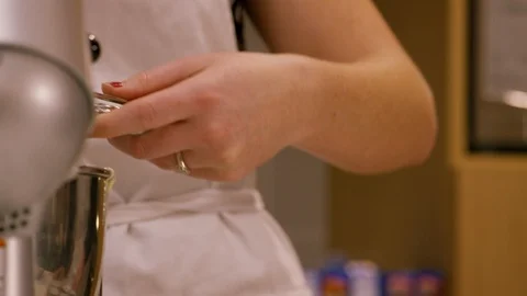 Baker pouring cupcake batter into trays from mixer bowl with ice cream scooper Stock Footage 111676982
