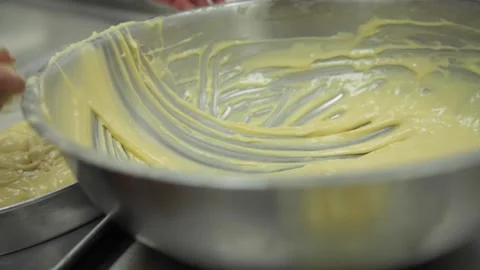 A baker pours cake batter into baking tray Stock Footage 231414779