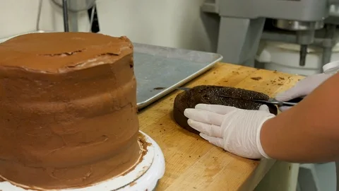 Baker prepares cake layer by cutting and smoothing Stock Footage 94242377