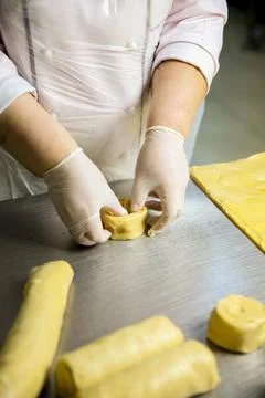 Baker prepares dough rolls at a kitchen table during the day Фото