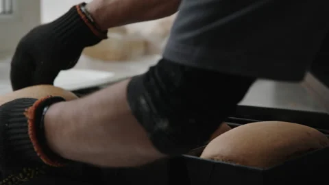 Baker prepares freshly baked bread in rectangular pans on a kitchen counter Video stock 345041775