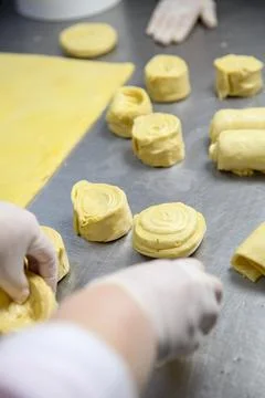 Baker prepares rolls of dough in a kitchen during baking session 库存照片
