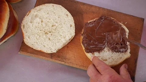 Baker prepares a slice of bread and spreads chocolate on it Stock Footage 337242645
