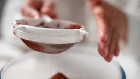Baker preparing chocolate dough on table. Chef sifting cocoa powder for doug Stock Footage 247367714