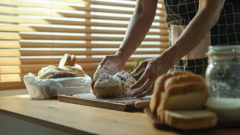 Baker preparing delicious fresh bread on wooden kitchen countertop.. Stock Photos