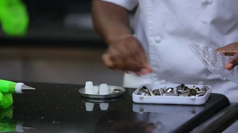 Baker preparing icing nozzle tips for decorating fancy cake Stock Footage 106944991