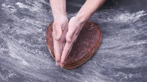 Baker presents handmade rye whole grain sourdough artisan bread in shape heart Stockbeeldmateriaal 130495300