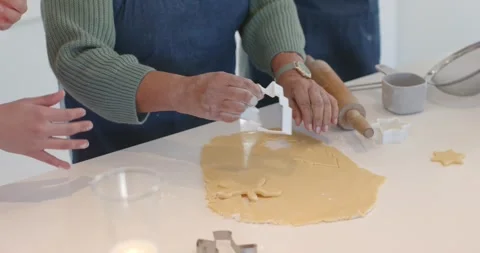 Baker is pressing tree cutter into rolled dough on counter after positioning, Video stock 345089386