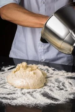 Baker pulling bread dough out of container Stock Photos