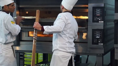 Baker pulling out of the electric oven a pizza Stock Footage 72550756