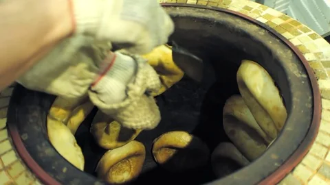 A baker is pulling Uzbek flapjacks out the tandoor. Stock Footage 79933991