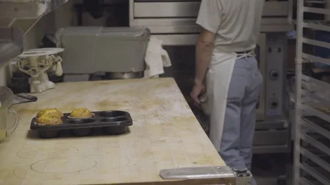 Baker pulls fresh muffins out of oven Stock Footage 73898785